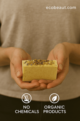 A person holds a rectangular botanical soap bar topped with dried herbs and flowers. The website ecobeaut.com is in the top right, with eco-labels 'NO CHEMICALS' and 'ORGANIC PRODUCTS' at the bottom.