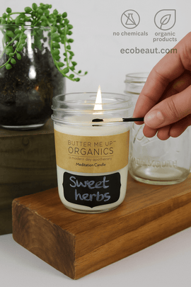 A person lights a 'Sweet Herbs' soy wax candle by Butter Me Up Organics during a cozy home ritual – ecobeaut.com – no chemicals, organic products