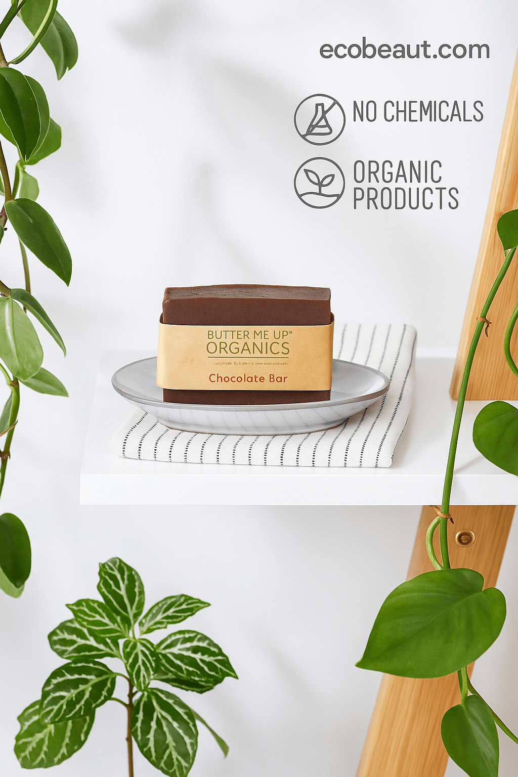 Butter Me Up Organics Chocolate Bar soap on a plate with striped cloth, surrounded by green plants, featuring “NO CHEMICALS,” “ORGANIC PRODUCTS” icons, and ecobeaut.com in the top right corner.