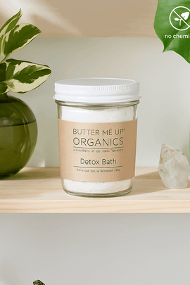 Butter Me Up Organics Detox Bath jar on wooden shelf with green plants and crystals – natural bath soak with Epsom salt and clay