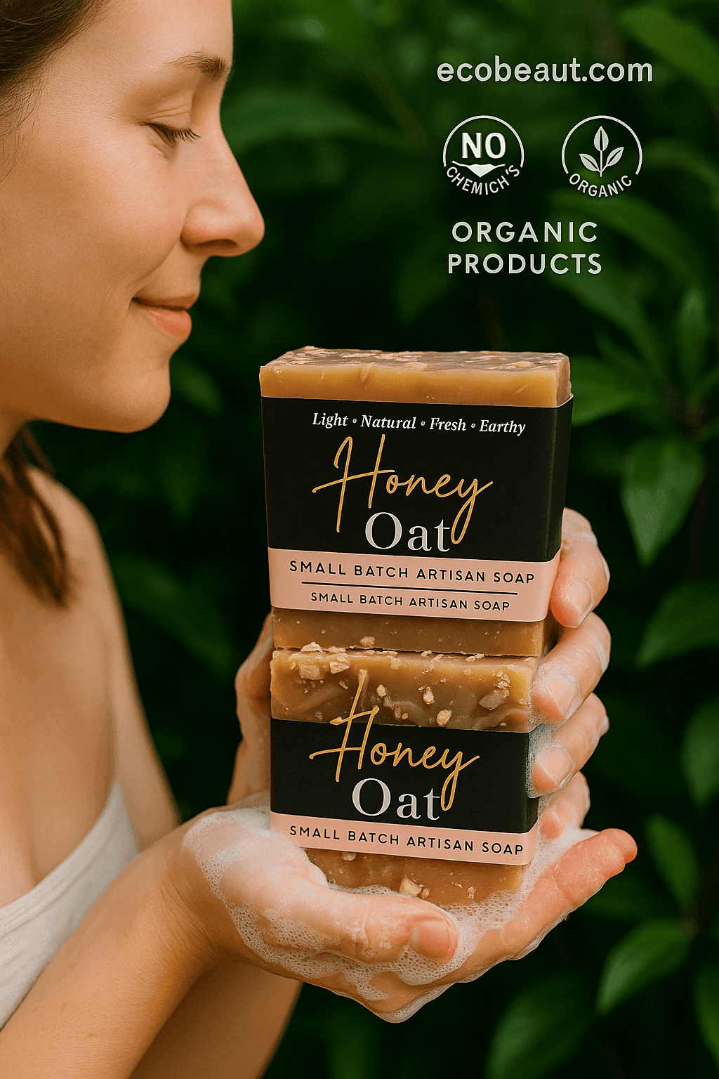 Caucasian woman gently washing her hands with Honey Oat artisan soap, holding two bars with visible lather, surrounded by lush greenery, with ecobeaut.com, “NO CHEMICALS,” and “ORGANIC PRODUCTS” icons in the top right corner.