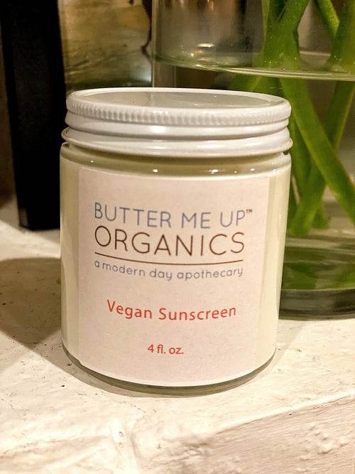 Close-up of Butter Me Up Organics vegan sunscreen jar on neutral background with ecobeaut.com, labeled no chemicals, organic products.