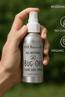 Close-up of a hand holding a Bug-Off Shake and Spray aluminum bottle outdoors, with no chemicals and organic products labels and ecobeaut.com shown in the top right corner.
