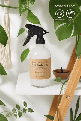Eco-friendly organic glass cleaner on a white shelf surrounded by green plants – Butter Me Up Organics, 16 oz, no chemicals, natural product