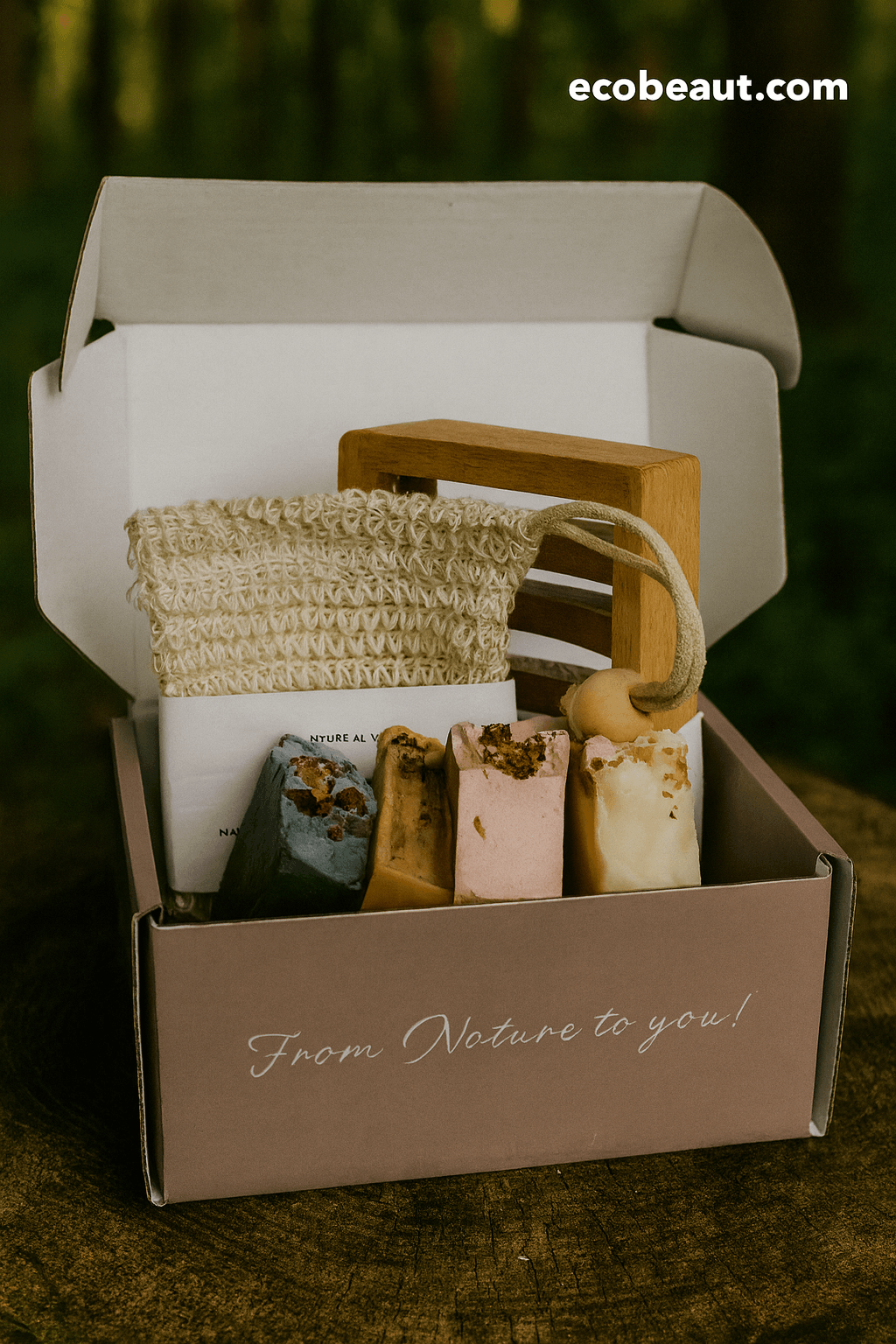 EcoBeaut.com Natural Soap Gift Box — eco-friendly set with four handmade soaps, wooden soap dish, and exfoliating loofah pouch, beautifully displayed outdoors on a rustic tree stump for organic skincare promotion in the USA.