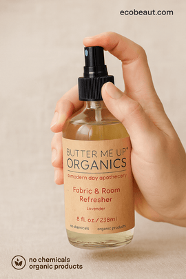 Hand holding Butter Me Up Organics lavender room spray with ecobeaut.com text and clean beige background – organic product used for natural air freshening