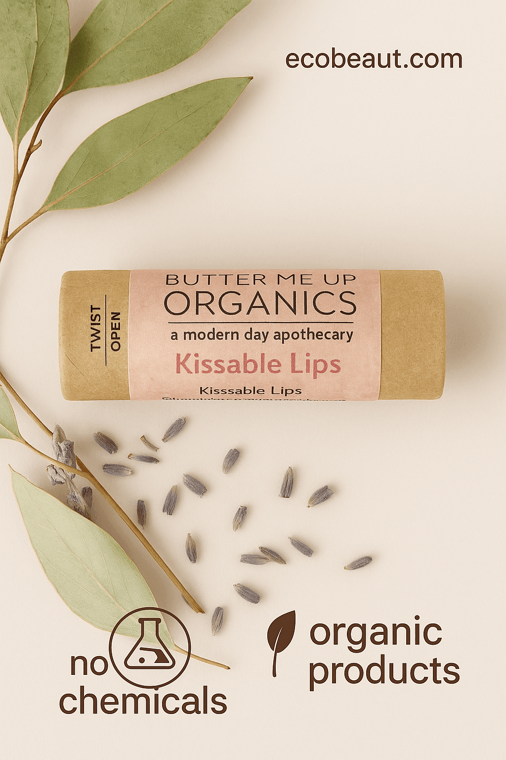 Kissable Lips organic lip balm by Butter Me Up Organics displayed on a rustic whitewashed wooden surface. The kraft paper tube with a pink label is surrounded by eucalyptus leaves and lavender, with “ecobeaut.com” written in the top right corner and eco-icons “no chemicals” and “organic products” placed neatly at the bottom.