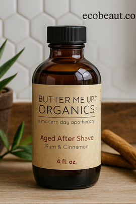 Butter Me Up Organics Aged After Shave bottle with cinnamon sticks and a plant in the background