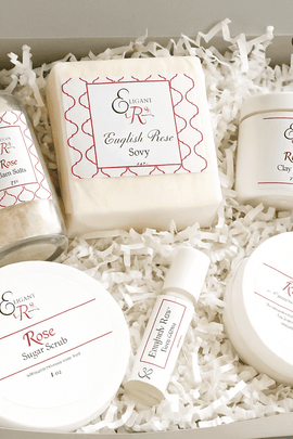 Open gray gift box featuring Elegant Rose skincare products including English Rose soap, bath salts, clay mask, scrub, and cream, neatly arranged in white shredded paper with ecobeaut.com in the top right corner.