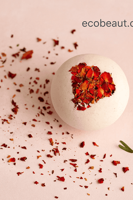 Rose petal bath bomb on a soft pink background with scattered petals and greenery – romantic handmade bath bomb by ecobeaut.com