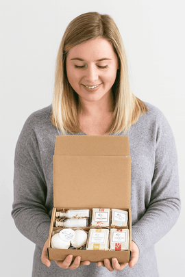 Woman holding eco-friendly gift set with natural handmade soaps, bath bombs, and organic skincare products in a kraft box – perfect sustainable gift idea, premium USA-made natural cosmetics for self-care and relaxation