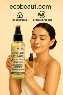 Young woman with smooth skin applying Almond & Honey Body Bliss Oil from Rinse Bath & Body Co., holding a golden spray bottle near her face with a gentle smile, standing against a beige background with eco-friendly labels and ecobeaut.com displayed in the top right corner