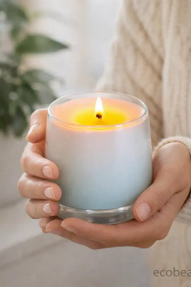 Person holding a lit candle in a light blue holder with a blurred background