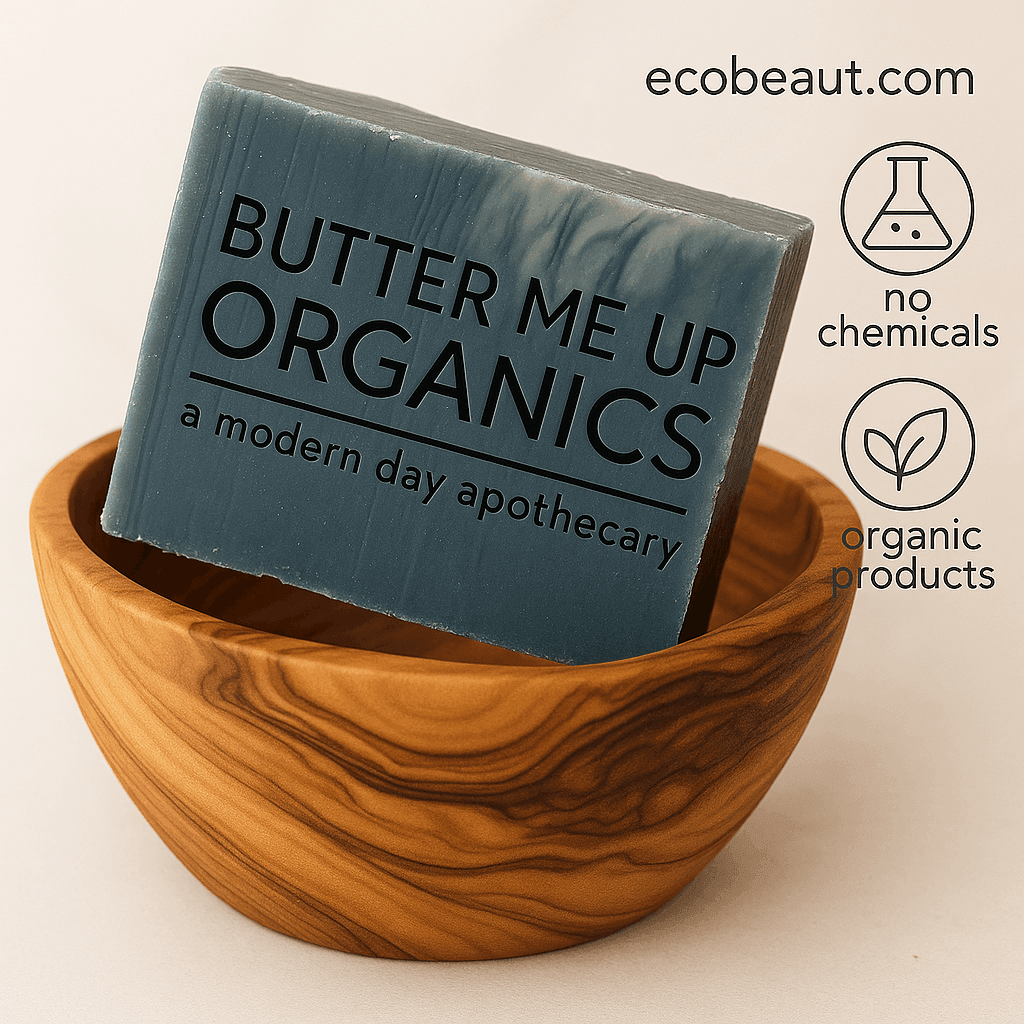 soap bar labeled 'Butter Me Up Organics' displayed in a carved wooden bowl with the text ecobeaut.com in the top right corner and icons reading 'no chemicals' and 'organic products' on a neutral background.