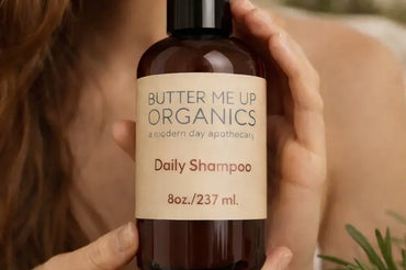 Woman holding Butter Me Up Organics Daily Shampoo bottle, natural organic shampoo presented in hands, eco-friendly packaging, clean beauty product for healthy hair – ecobeaut.com