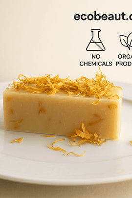  A handmade calendula soap bar by ecobeaut.com rests on a white ceramic plate, topped with dried petals, with “NO CHEMICALS” and “ORGANIC PRODUCTS” icons in the upper right corner.



