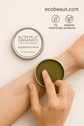 A person applying Butter Me Up Organics Bug Bite/Itch Relief balm to their forearm with fingers, shown with open tin on beige background, eco labels “no chemicals,” “organic products,” and ecobeaut.com in the top right corner.