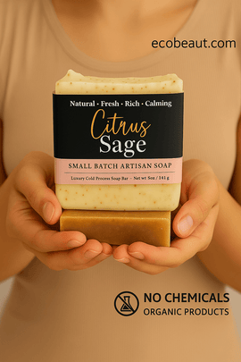 A woman holds a bar of Citrus Sage artisan soap with both hands. The label highlights its natural and calming qualities. ecobeaut.com is displayed in the top right corner, and eco icons 'NO CHEMICALS' and 'ORGANIC PRODUCTS' are shown at the bottom.
