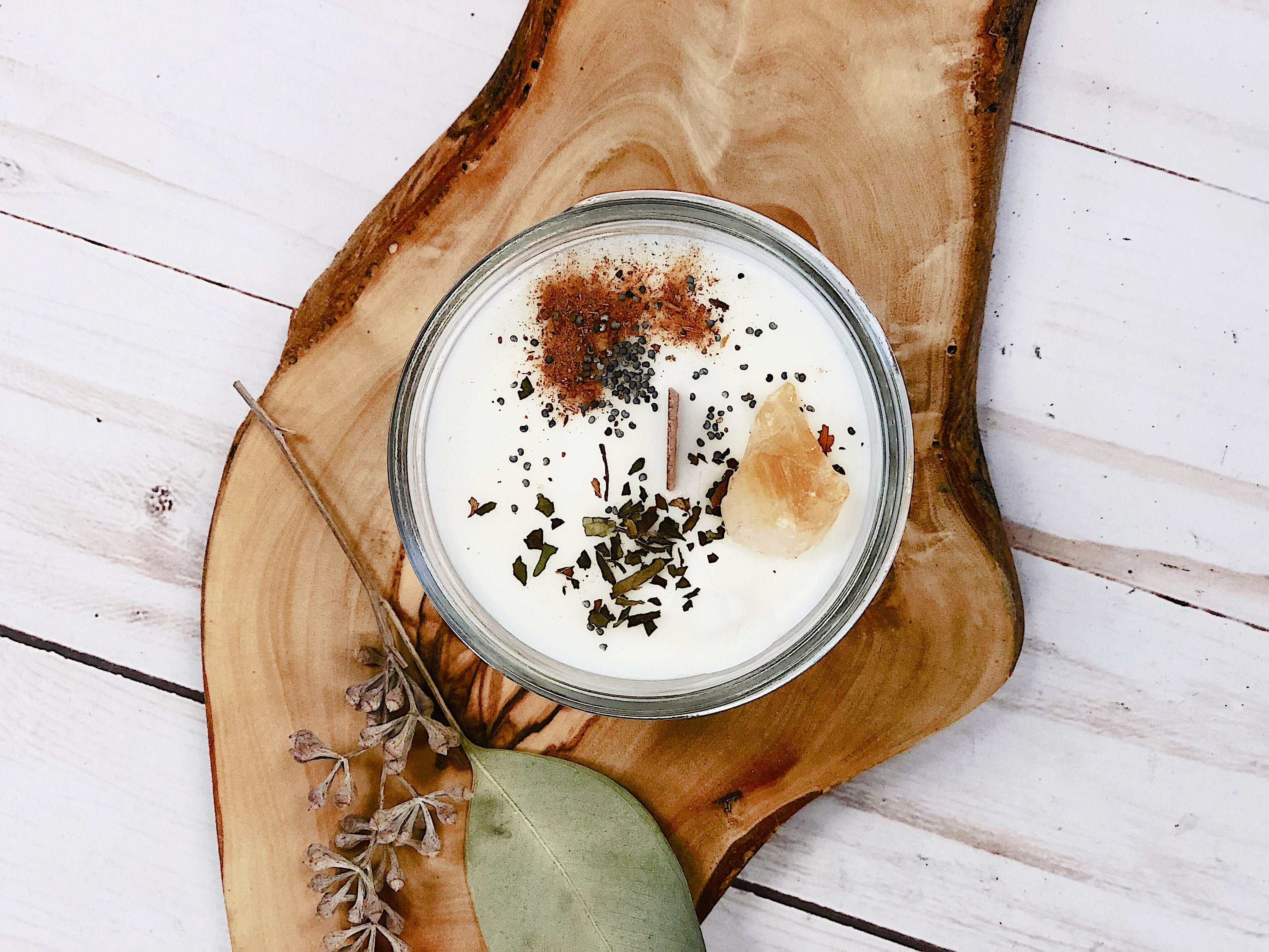 Candle in a glass jar with decorative elements on a wooden board