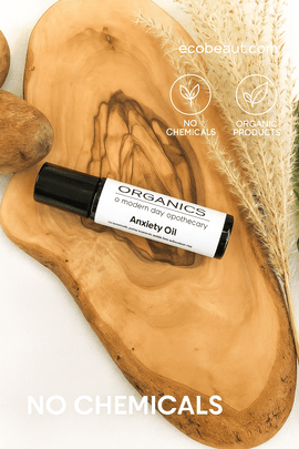 "Anxiety Oil roller bottle on wood slice with pampas grass, eco labels, and ecobeaut.com branding in the top right corner."