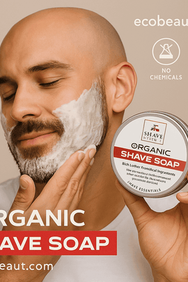 Bald man with a trimmed beard applying Shave Essentials Organic Shave Soap to his face, holding the product tin with visible label, accompanied by ecobeaut.com and eco icons promoting no chemicals and organic ingredients.