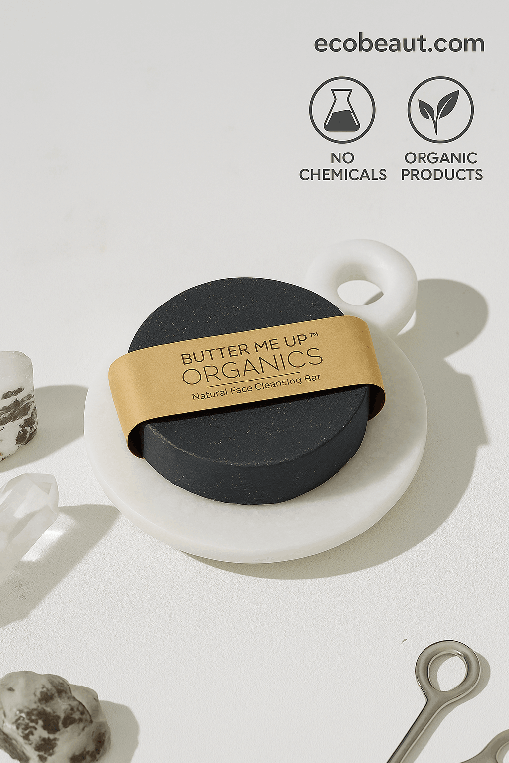  Black round soap bar labeled “Butter Me Up Organics” on a white marble dish with crystal stones, featuring “NO CHEMICALS,” “ORGANIC PRODUCTS” icons, and ecobeaut.com in the top right corner.