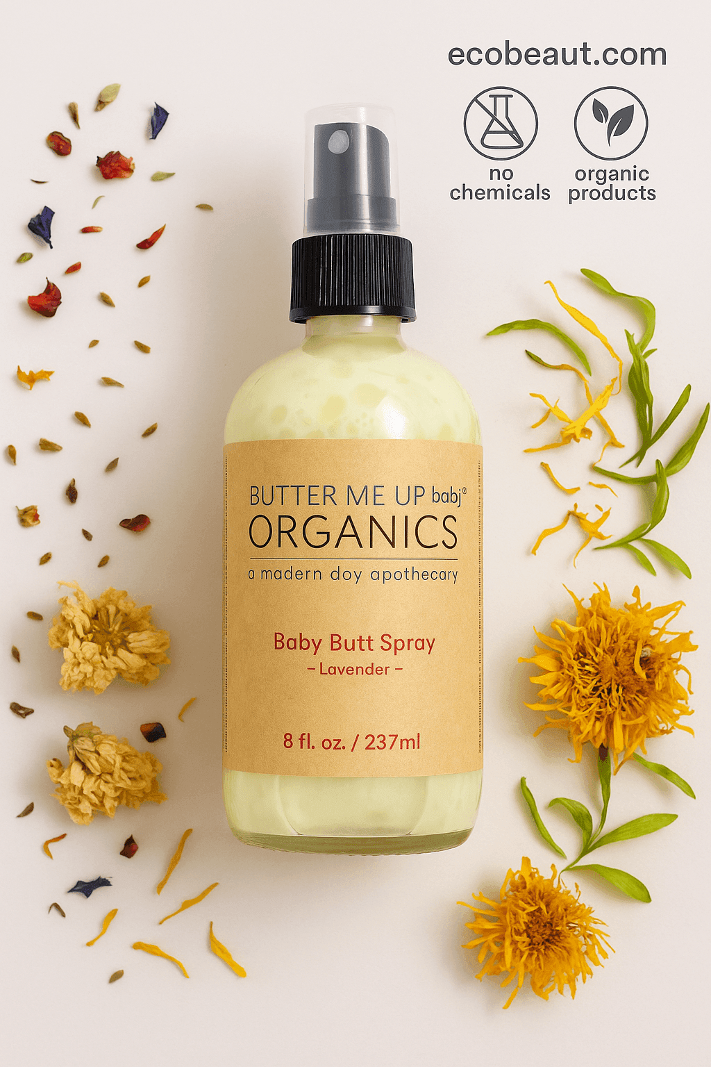 Butter Me Up Organics Baby Butt Spray bottle with kraft label lies on a light background surrounded by colorful dried flowers. Eco-friendly icons and ecobeaut.com appear in the top right corner.





