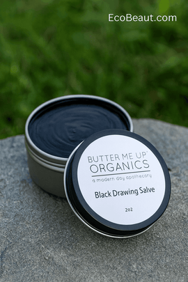 Butter Me Up Organics Black Drawing Salve tin on natural stone with green nature background, eco-friendly organic healing balm, EcoBeaut.com branding