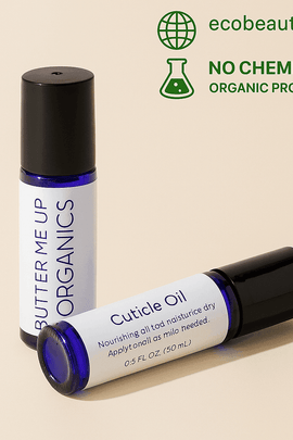 Butter Me Up Organics Cuticle Oil and roll-on bottle on beige background. Organic, chemical-free nail care products with ecobeaut.com branding in the top corner.