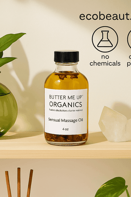 Butter Me Up Organics Sensual Massage Oil on a wooden shelf with green plants and a crystal. Soft lighting and top right includes ecobeaut.com and icons: no chemicals, organic products.