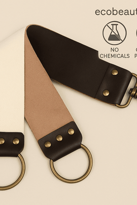 Close-up of a leather and canvas straight razor strop featuring brass hardware, displayed on a soft beige background with eco-friendly icons and ecobeaut.com branding in the top-right corner.