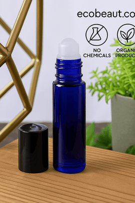 "Custom perfume oil in a cobalt blue roll-on bottle with black cap, placed on a wooden surface, decorated with lush green plants and eco labels 'no chemicals', 'organic products', and ecobeaut.com branding in the top right corner."