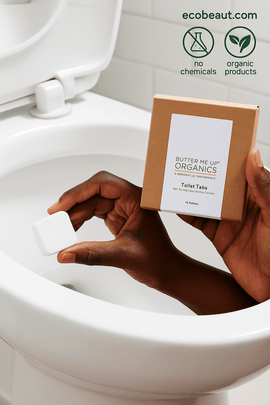 Dark-skinned hand using Butter Me Up Organics Toilet Tabs – natural fizzing tablet held near toilet, plastic-free and non-toxic cleaner