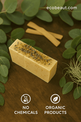 Handcrafted botanical soap bar with dried herbs on top, placed on a wooden surface surrounded by fresh green leaves. The website ecobeaut.com is in the top right corner, and icons reading 'NO CHEMICALS' and 'ORGANIC PRODUCTS' are shown at the bottom.
