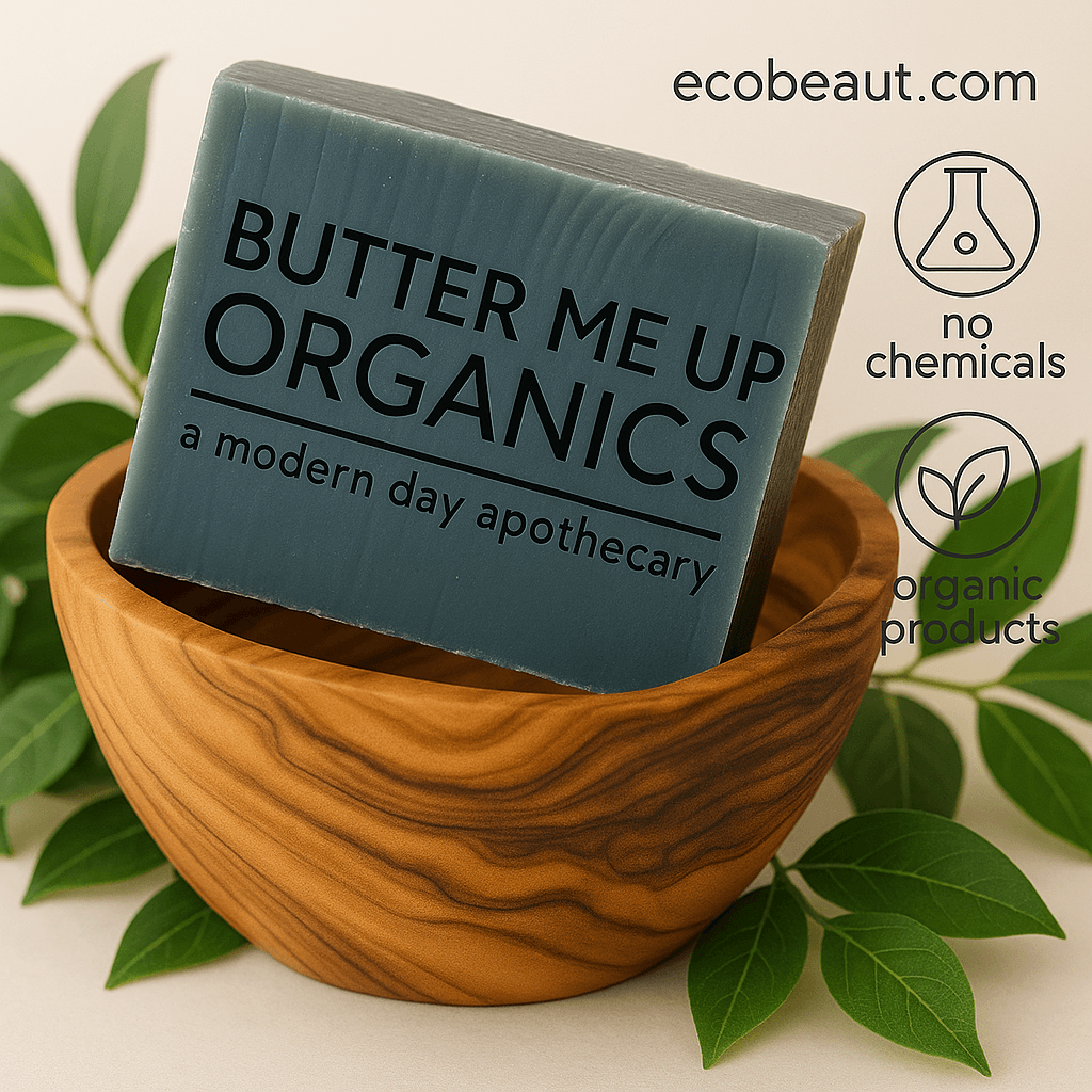 Handcrafted soap bar labeled 'Butter Me Up Organics' in a carved wooden bowl surrounded by green leaves, with icons reading 'no chemicals' and 'organic products' and the website ecobeaut.com in the top right corner.