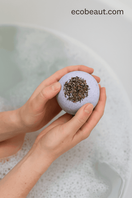 Hands holding a lavender bath bomb above a foamy bath – soothing aromatherapy experience from ecobeaut.com