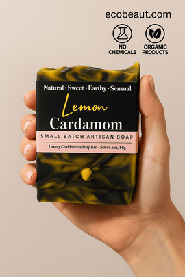 Lemon Cardamom artisan soap bar in natural use by a person, surrounded by green leaves, with "no chemicals," "organic products" icons and ecobeaut.com in the top right corner