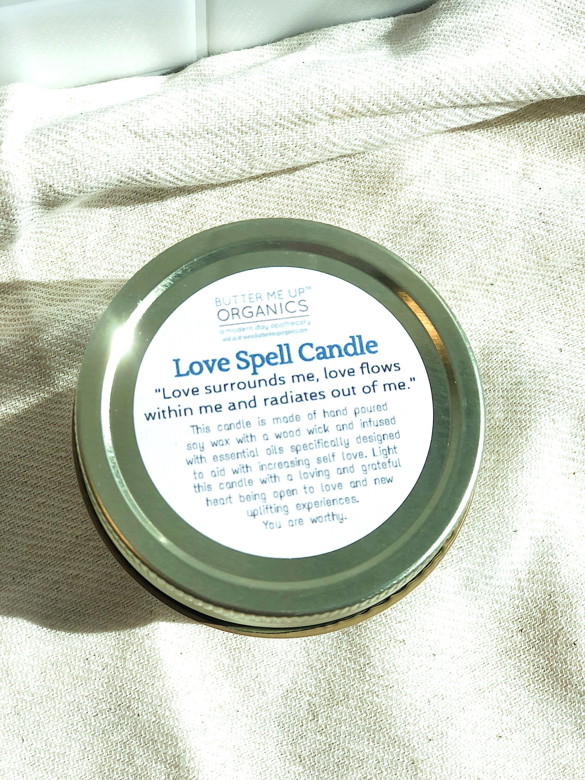 Love Spell Candle lid with text on a light fabric background