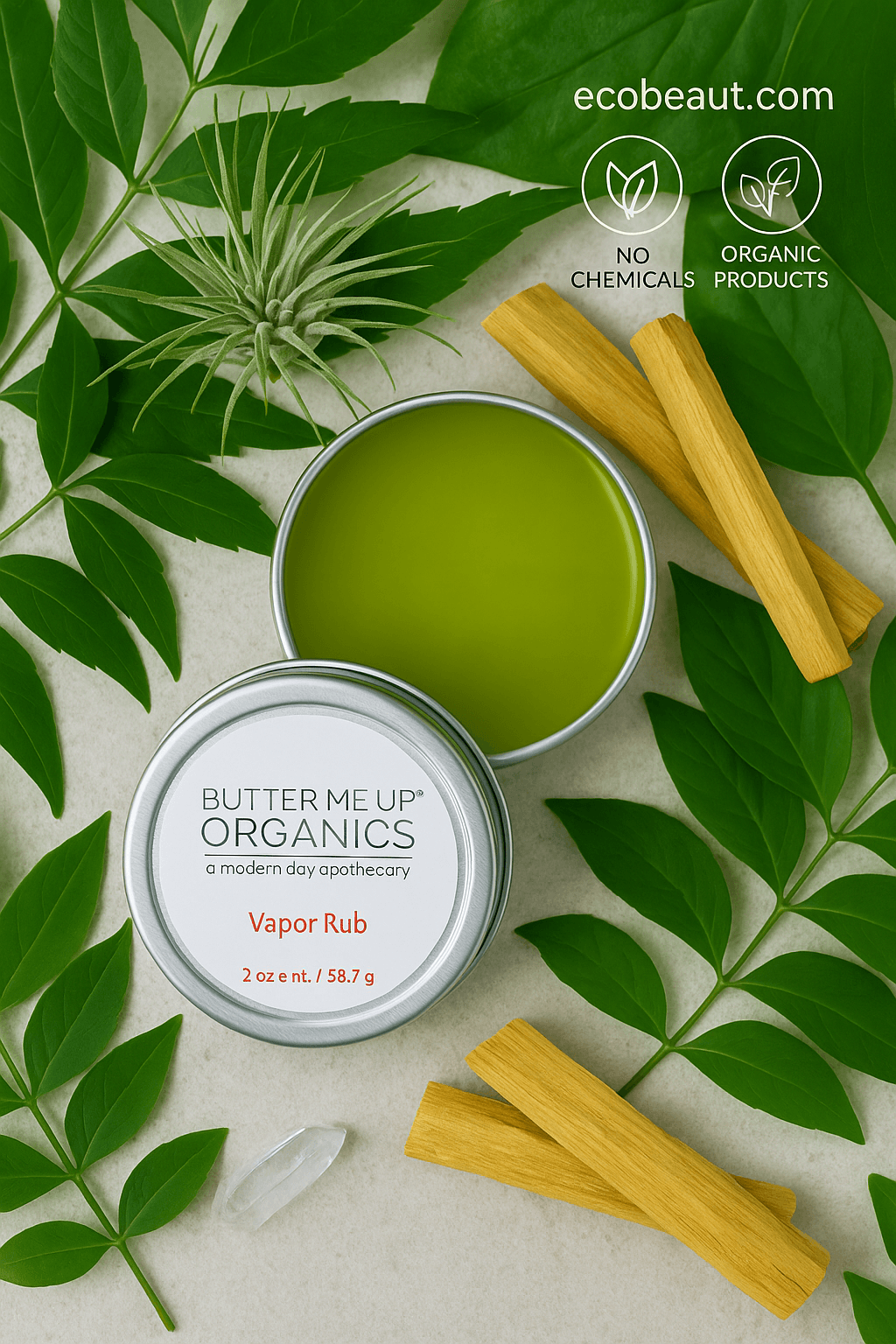 "Open tin of Butter Me Up Organics Vapor Rub on natural surface, surrounded by green leaves, palo santo sticks, eco labels, and ecobeaut.com branding in the top right corner."





