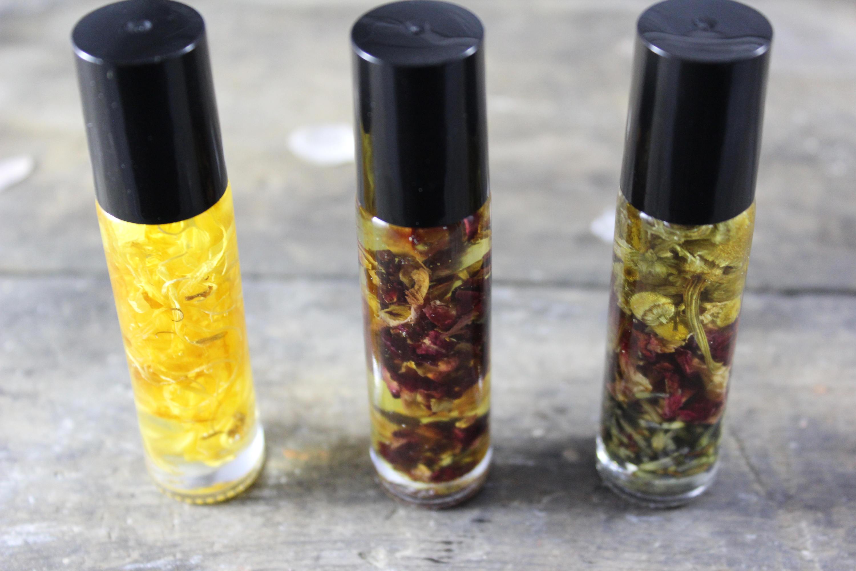 Three small glass bottles with black lids containing yellow and red liquid mixtures on a wooden surface.