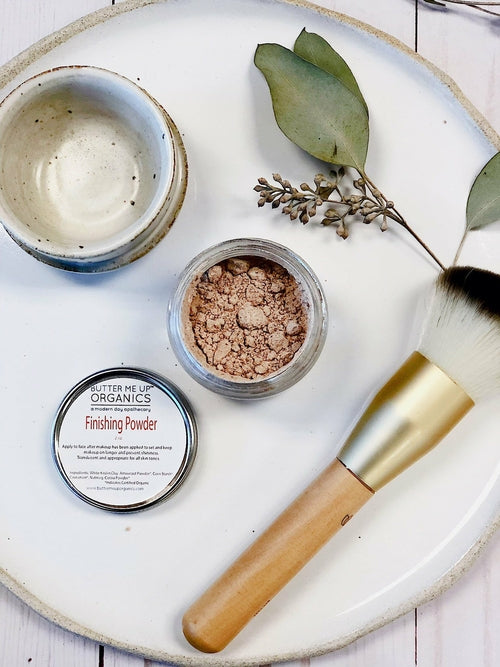 Finishing powder jar with a brush and leaf on a white plate