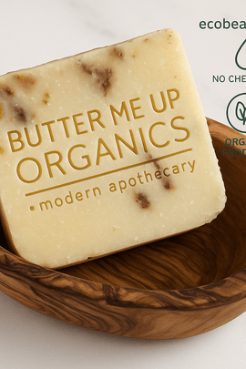 Organic soap bar with herbal streaks in handcrafted wooden bowl, labeled Butter Me Up Organics – ecobeaut.com
