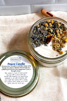 Peace Candle packaging with lid open showing lavender and wood chips on a beige cloth.