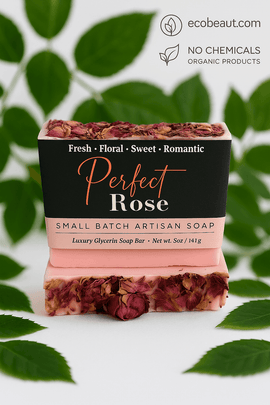 Perfect Rose artisan soap bar by ecobeaut.com surrounded by fresh green leaves, with “NO CHEMICALS” and “ORGANIC PRODUCTS” icons in the top right corner.