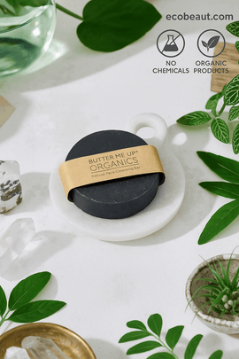 Butter Me Up Organics product on a white surface with green leaves and a glass container.