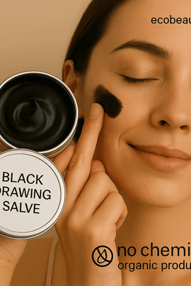 Smiling woman applying Black Drawing Salve to her cheek with her finger, holding an open tin of the product. The label reads “Black Drawing Salve,” with “ecobeaut.com” in the top right and markings “no chemicals” and “organic products” at the bottom.








