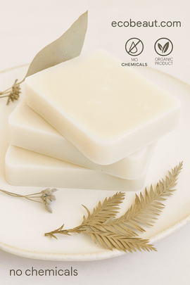Stack of three handmade white soap bars on a ceramic plate with dried botanicals, featuring ecobeaut.com and “NO CHEMICALS” / “ORGANIC PRODUCT” icons in the upper right corner.