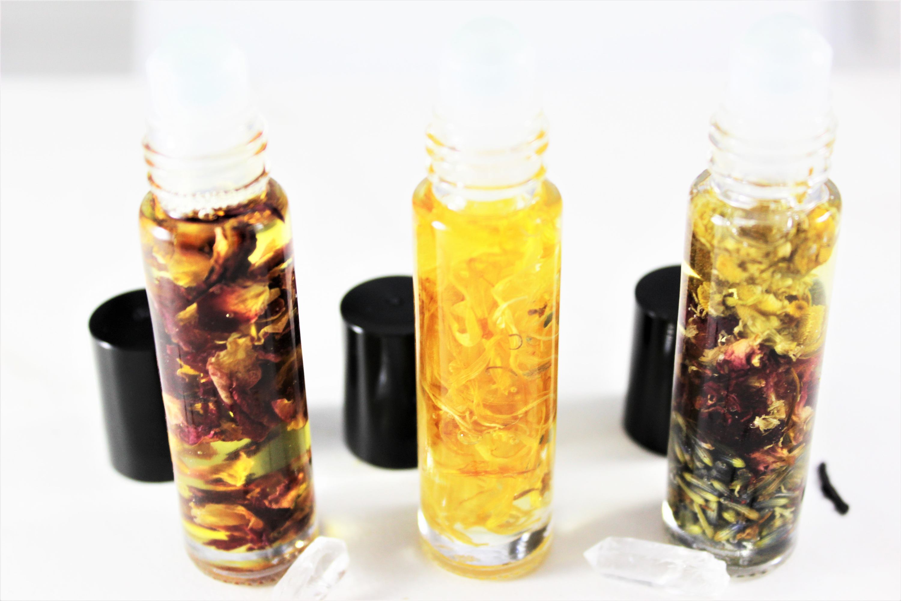 Three glass bottles with liquid and floating herbs on a white background