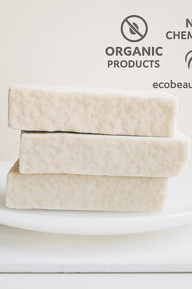 Three handcrafted off-white soap bars stacked on a white plate with “NO CHEMICALS,” “ORGANIC PRODUCTS” icons and ecobeaut.com in the top right corner.