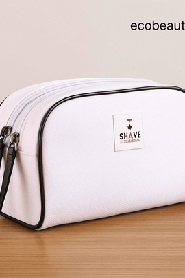 White Shave Essentials toiletry bag with black trim and dual zippers displayed on a wooden surface, featuring ecobeaut.com text in the upper right corner to highlight brand identity.